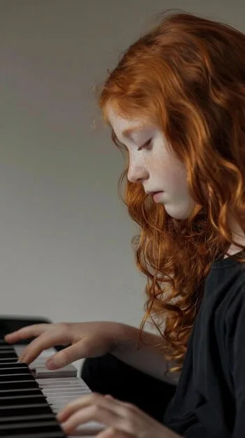 A young girl, aged around 5, looking intently at sheet music while playing a small keyboard, her brow slightly furrowed in concentration. The background is softly blurred, highlighting her focus.