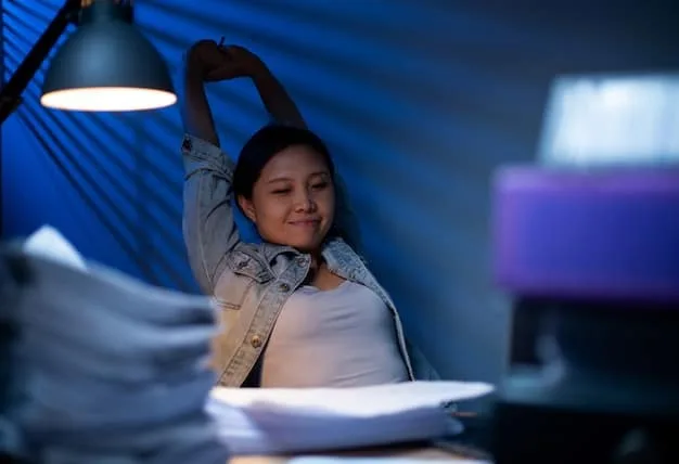 A Gen Z student looking stressed while trying to study at night, surrounded by electronic devices emitting blue light, showcasing their struggle with sleep.