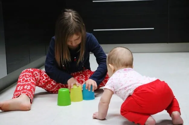 A baby around 6 months old, sitting up and reaching for a toy, showing purposeful interaction and developing motor skills.
