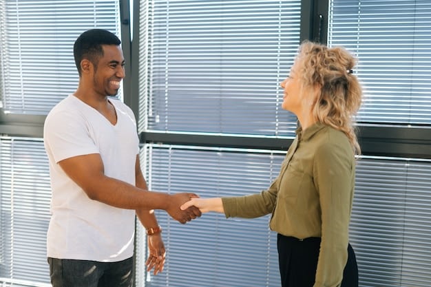 Two people shaking hands after reaching an agreement, symbolizing trust and mutual respect. The background shows a diverse team working together on a project.