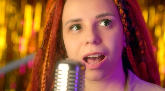 A close-up shot of a young female artist with trendy hair and makeup, singing passionately into a microphone on stage during a vibrant pop concert.