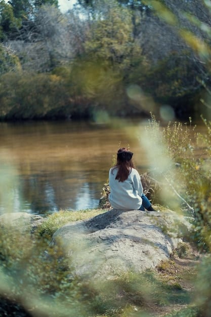A person sitting in a meditative pose outdoors, surrounded by nature, eyes closed, with a serene expression, exemplifying mindful gratitude.
