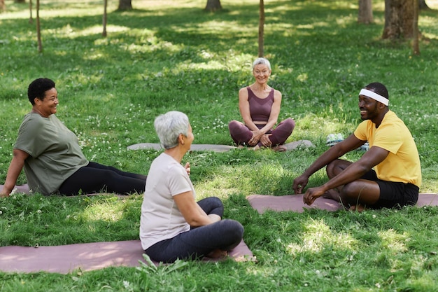 A diverse group of people participating in a yoga class outdoors, focusing on their breathing and poses, with an instructor guiding them.