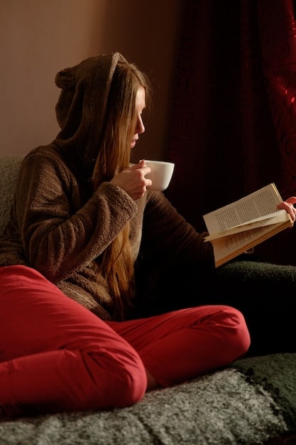 A woman smiling while reading a book in a cozy, sunlit room, conveying the importance of mental self-care.