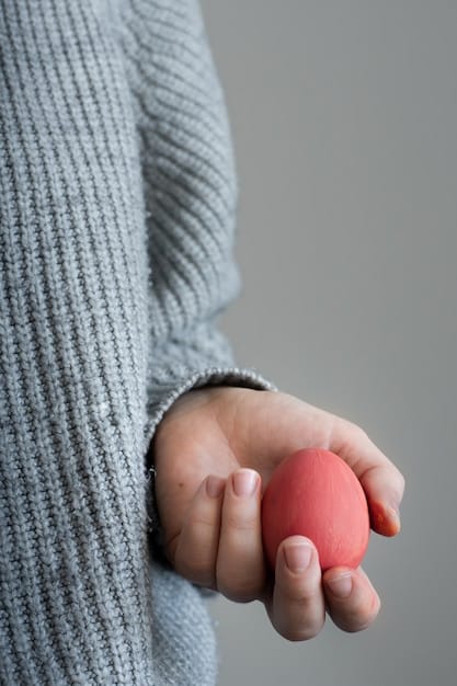 A hand holding a stress ball, squeezed tightly. The background is blurred, suggesting a classroom or study environment. The image conveys the physical manifestation of stress relief.