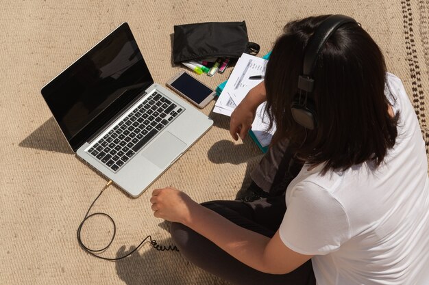 A Gen Z student on a laptop, surrounded by open books and digital devices, representing critical media consumption.