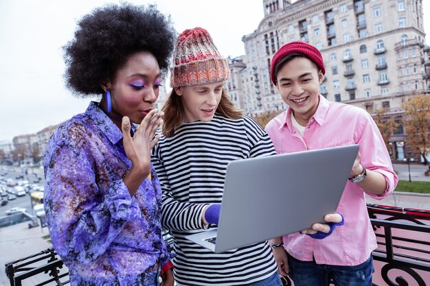 A digitally enhanced image of two diverse Gen Z individuals collaborating on a laptop, surrounded by floating social media icons and glowing chat bubbles, symbolizing collaborative digital communication.