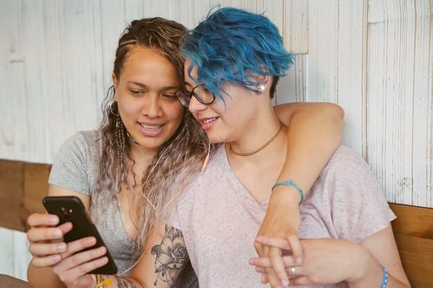 A Gen Z individual (likely non-binary or gender-neutral) thoughtfully engaging with a mobile device, possibly participating in an online community or learning, with a subtle background suggesting a blend of digital and physical environments.
