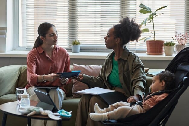 A diverse group of parents and caregivers attentively listening to an early intervention specialist, with colorful early learning materials visible in the background, depicting a collaborative and supportive environment.