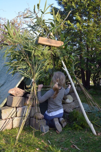 Two children building a fort with sticks and leaves, symbolizing creative play and collaboration in an outdoor setting.