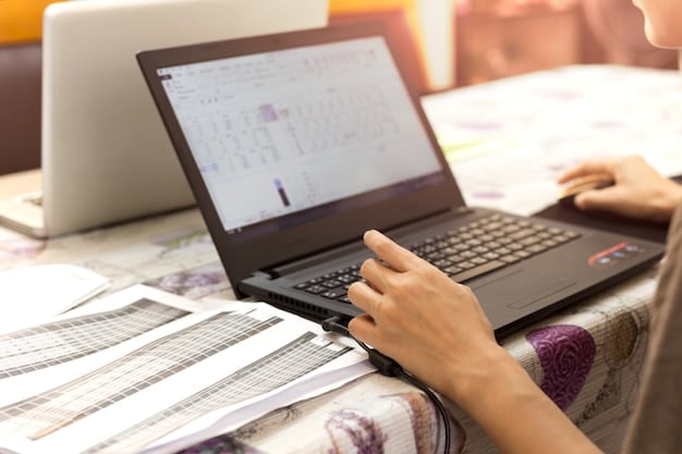 A close-up of hands typing on a laptop, with a blurred spreadsheet of financial data in the background, illustrating financial analysis and policy planning regarding student loans.