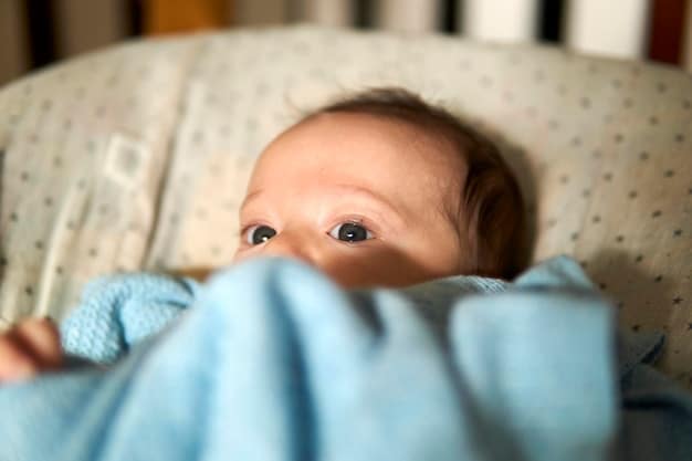 A calm, contented baby around 2 months old, lying on their back in a crib, gently sucking on their fist while looking towards the camera, indicating self-soothing or early hunger.