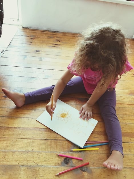 A child drawing their feelings with colorful crayons on a large piece of paper, while an adult sits beside them attentively, illustrating creative expression and supportive interaction.