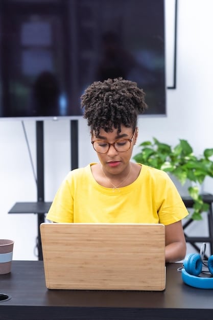 A student, possibly Gen Z, sitting at a desk with a laptop open, but looking thoughtfully away from the screen, perhaps in contemplation or problem-solving. The setting should be a modern, bright study space, implying focused academic work and deep thinking. Books or notes can be subtly present, reinforcing the academic context.